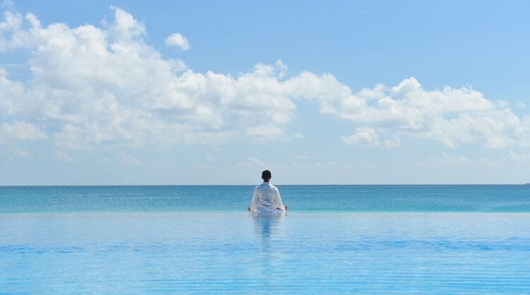 Homem em frente do oceano meditando detox mental